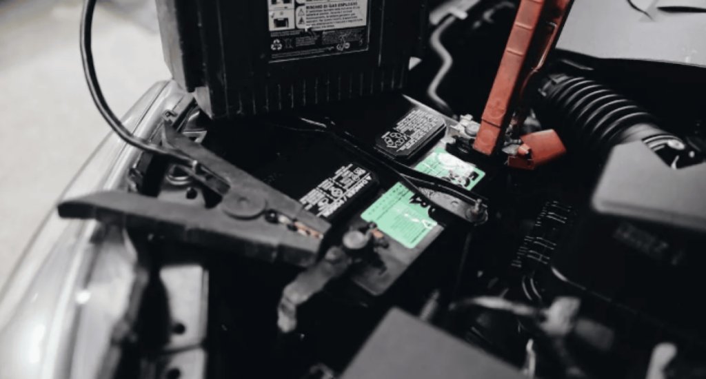 Car battery with jumper cables connected in the engine bay