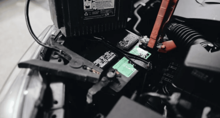 Car battery with jumper cables connected in the engine bay